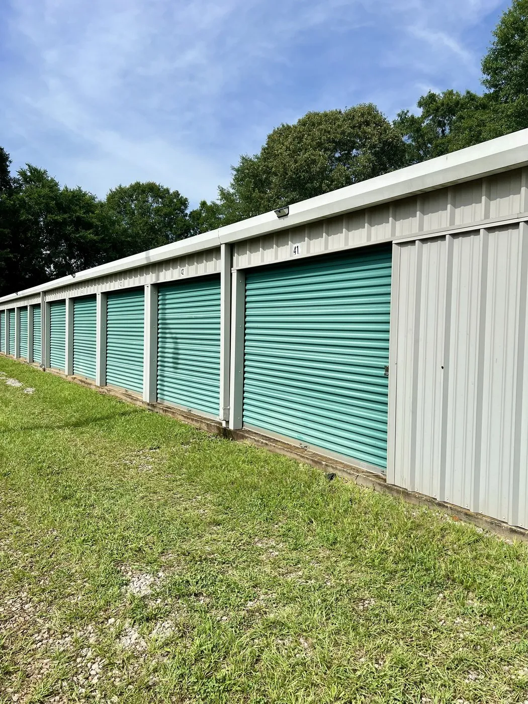 Marion Storage Depot Lafayette facility: a long row of numbered teal roll-up doors with grass and sky