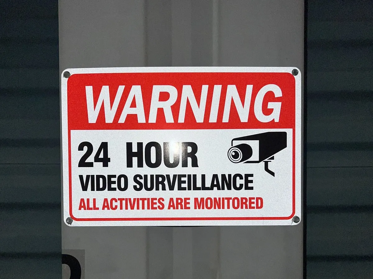 A posted warning sign reading 24 hour video surveillance, all activities are monitored